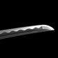 Close-up of the blade tip of the Japanese artisanal katana Hana no Yuki on a solid black background, highlighting the polished steel kissaki, the subtle wavy hamon line along the cutting edge, and the smooth curvature of the blade with visible bo-hi groove
