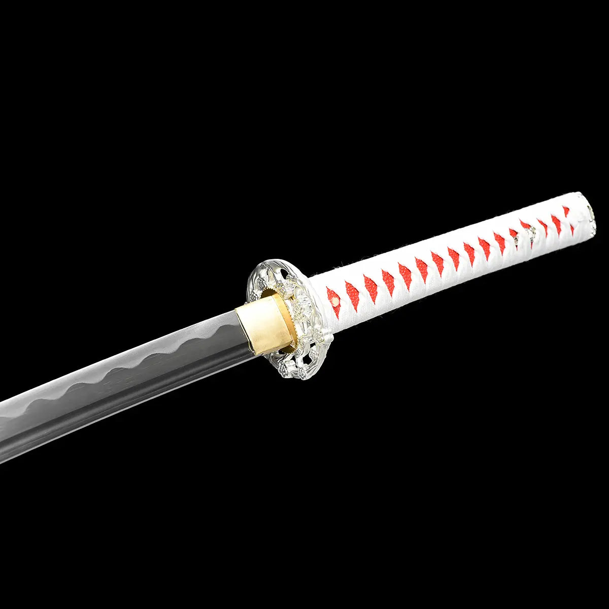 Close-up view of the Japanese artisanal katana Hana no Yuki on a solid black background, focusing on the junction between the blade and handle, showing the polished steel blade with subtle hamon, a gold-colored brass habaki, an ornate silver floral tsuba, and a white tsuka wrapped in white ray skin with red ito diamond pattern
