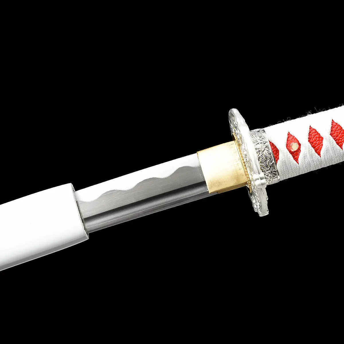 Close-up view of the Japanese artisanal katana Hana no Yuki partially drawn from its white lacquered saya on a solid black background, showing the polished steel blade with subtle wavy hamon, the gold-colored brass habaki seated at the mouth of the saya, part of the ornate silver floral tsuba, and the white tsuka wrapped in white ray skin with red ito diamond pattern
