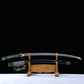 Katana japonais artisanal Seiryū no Tachi photographié sur fond noir avec base claire, présenté en pleine longueur sur un support en bois sculpté. La lame courbe en acier carbone est entièrement visible hors du fourreau, révélant un hamon réel ondulé sur toute la longueur. Le fourreau noir laqué est positionné sous la lame, avec son sageo tressé vert, blanc et pourpre. Le manche est recouvert d’un tsuka-ito vert foncé laissant apparaître une same blanche en losanges, et les montures métalliques traditionnel