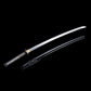 Katana japonais artisanal Shinshi no Ken présenté lame dégainée au-dessus de son fourreau noir laqué sur fond noir profond, lame en acier poli avec hamon ondulé visible, habaki doré, poignée noire avec tressage traditionnel laissant apparaître un samegawa blanc et fourreau équipé d’un sageo gris foncé nou
