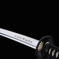 Gros plan sur la lame gravée du katana japonais artisanal Shinshi no Ken sur fond noir profond, acier poli avec hamon ondulé visible, inscription japonaise nette le long de la lame, tsuba noire nervurée et manche noir avec tressage traditionnel laissant apparaître un samegawa blanc.
