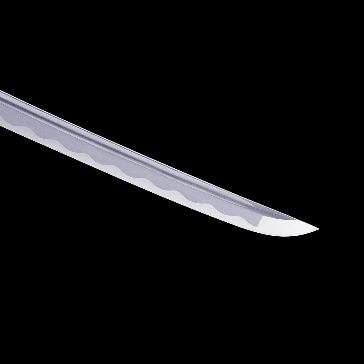 Gros plan sur la pointe kissaki du katana japonais artisanal Shinshi no Ken sur fond noir profond, lame en acier poli avec hamon ondulé clairement visible le long du tranchant, géométrie de lame nette et finition brillante sans fourreau ni poignée visibles.
