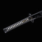 Détail du manche (tsuka) du katana japonais artisanal Shinshi no Ken sur fond noir profond, poignée noire avec tressage en losanges laissant apparaître un samegawa blanc, menuki dorés visibles sous le laçage, tsuba noire nervurée et fourreau noir laqué partiellement visible à l’arrière.
