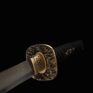 Détail de la garde (tsuba) en laiton ciselé du katana japonais de combat Okinawa, décor de vagues et finitions artisanales.