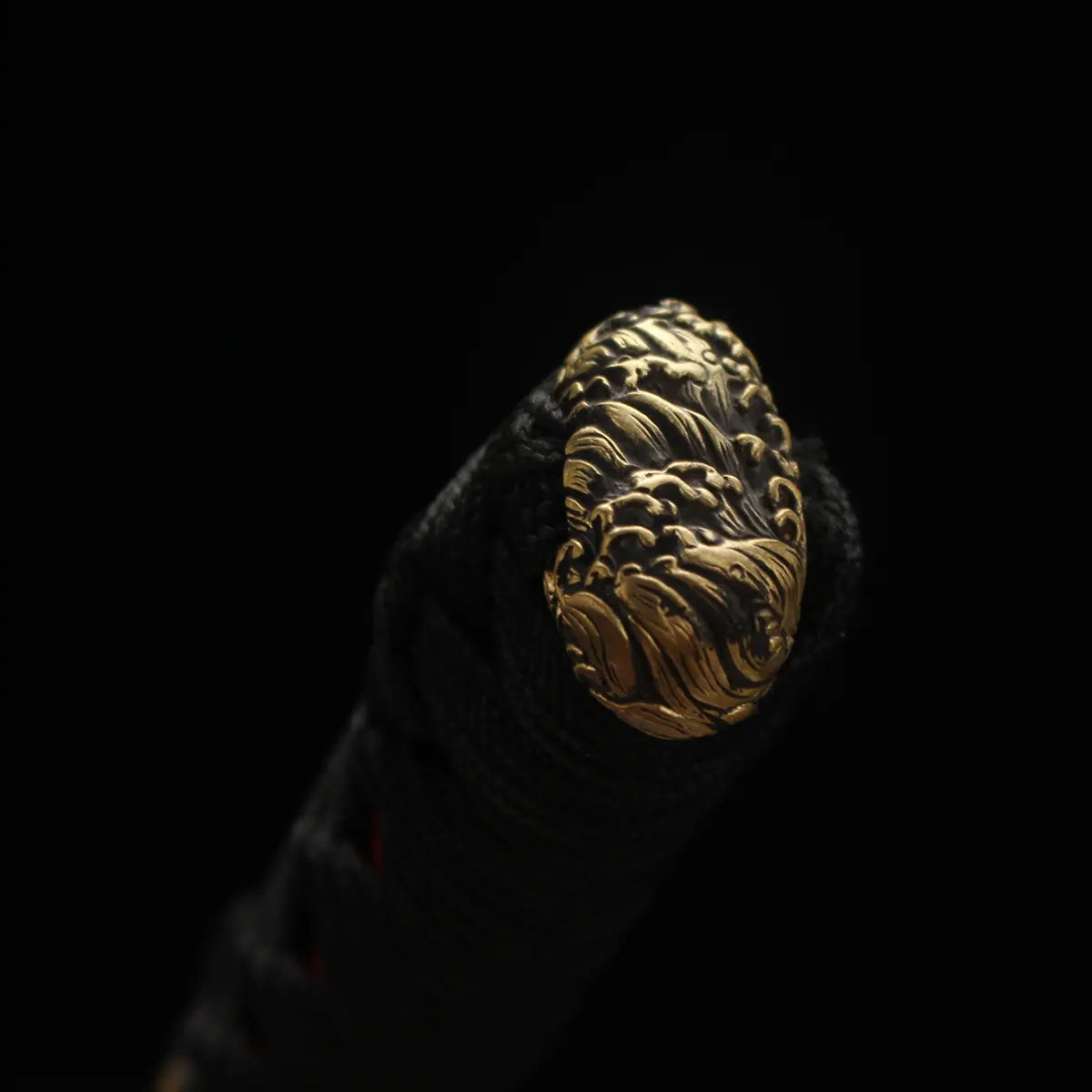 Gros plan sur le kashira (pommeau) en laiton sculpté motif de vagues, finition haut de gamme du katana de combat Okinawa.