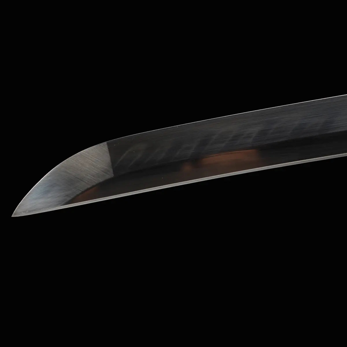 Gros plan sur la pointe (kissaki) tranchante du katana japonais de combat Okinawa, hamon visible sur l’acier T10 poli.