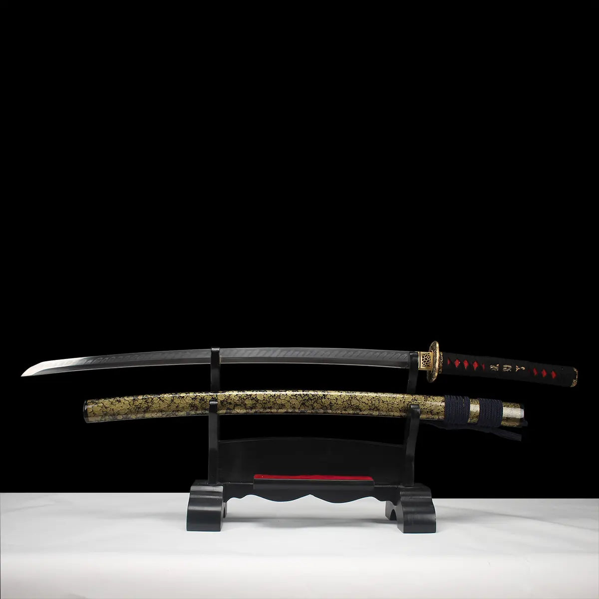 Katana japonais de combat Okinawa en acier T10, lame entière exposée sur support en bois noir, fourreau doré veiné noir, fond studio sombre.