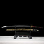 Katana japonais de combat Okinawa en acier T10, lame entière exposée sur support en bois noir, fourreau doré veiné noir, fond studio sombre.