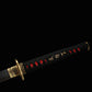 Vue rapprochée du tsuka du katana japonais de combat Okinawa, tressage coton noir, peau de raie rouge et menuki dorés traditionnels.
