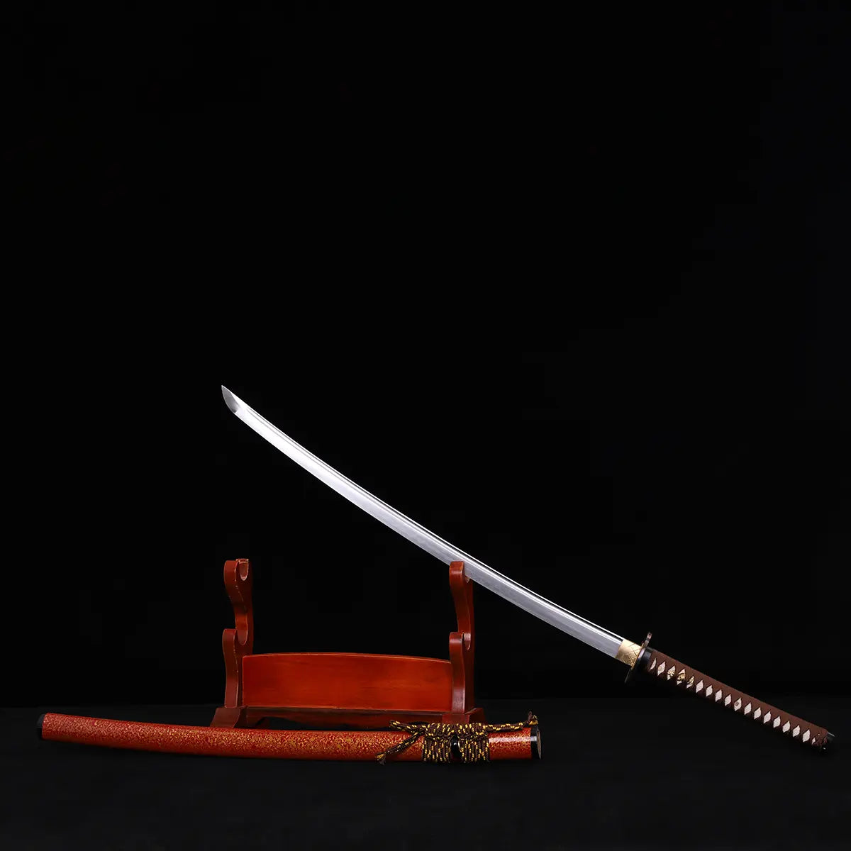Katana japonais Kannon Ryū exposé sur support en bois verni, lame acier 1045 dégainée et saya rouge laqué moucheté or posé à côté, sur fond noir studio Blade Bushido.