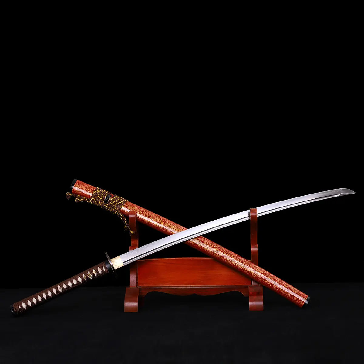Katana japonais Kannon Ryū présenté sur support en bois verni, lame acier 1045 dégainée au-dessus du saya rouge laqué moucheté or, sur fond noir studio Blade Bushido.