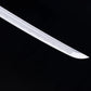 Gros plan sur la pointe kissaki du katana japonais “Kurenai no Tsuki”, lame brillante en acier forgé avec hamon ondulé traditionnel, photographiée sur fond noir – katana de collection Blade Bushido.