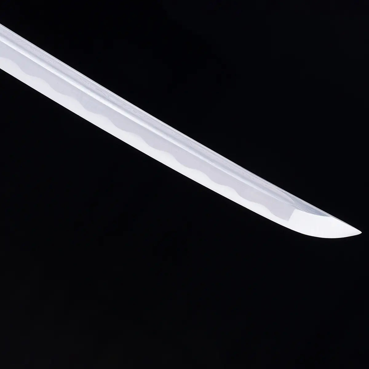 Gros plan sur la pointe kissaki du katana japonais “Kurenai no Tsuki”, lame brillante en acier forgé avec hamon ondulé traditionnel, photographiée sur fond noir – katana de collection Blade Bushido.