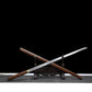 Katana japonais Shirasaya en acier 1060 avec hamon visible, monture bois de rose et support décoratif.