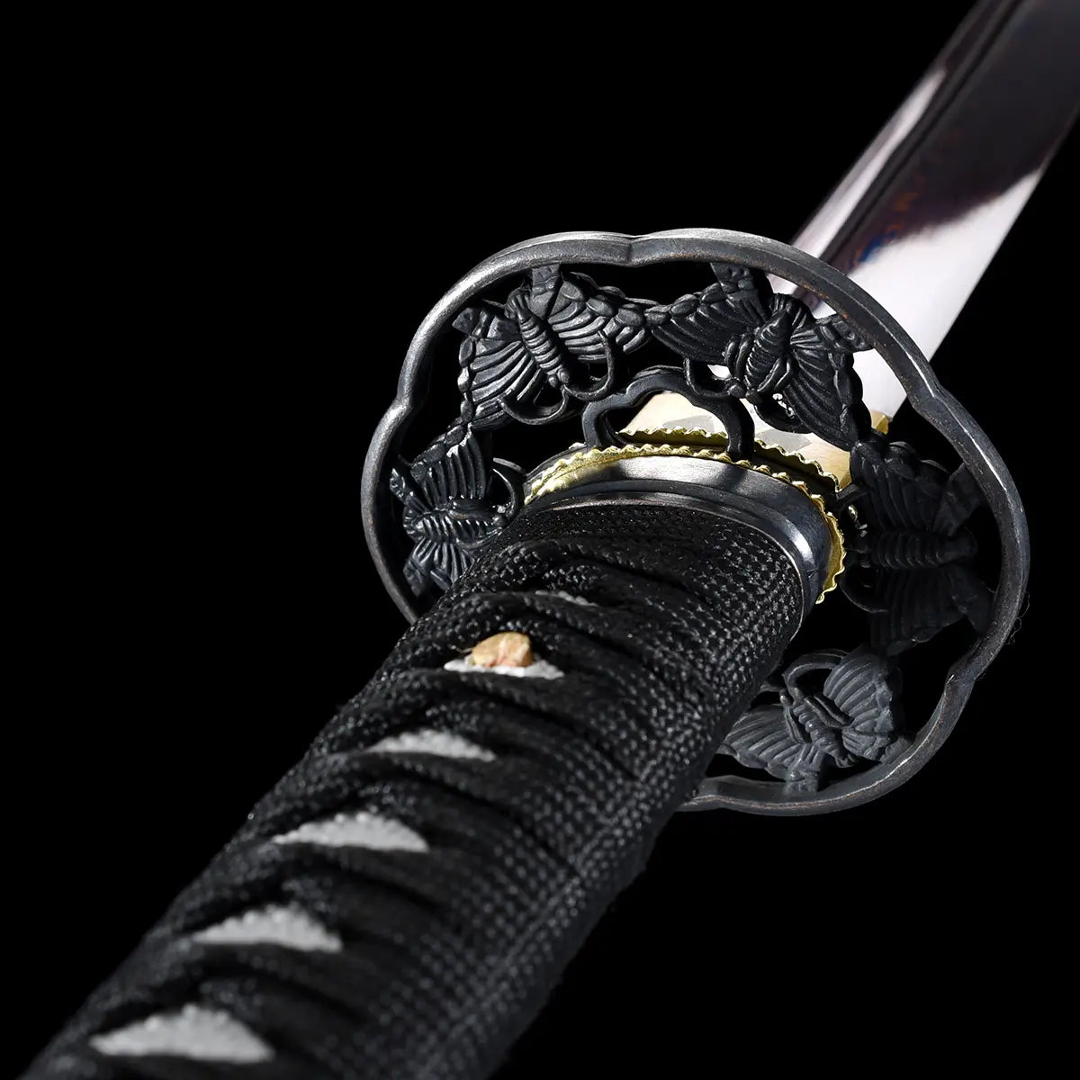 Détail de la tsuba ciselée noire et du tsuka en simili-cuir noir du katana japonais Tomoe Gozen.