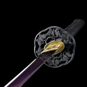 Vue rapprochée de la tsuba noire ciselée et du habaki doré gravé du katana japonais Tomoe Gozen.