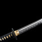Gros plan du katana nodachi Monohoshizāo artisanal : lame polie avec hamon réel ondulé (trempe à l’argile), habaki et seppa en laiton, tsuba ronde noire, tsuka noire à losanges ivoire (samegawa), sur fond studio noir — hommage à Sasaki Kojirō, esprit ōdachi élégant.