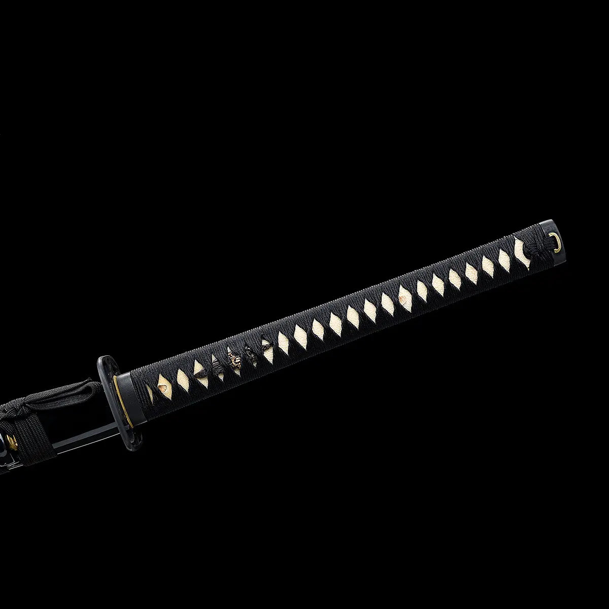 Gros plan de la tsuka du katana nodachi “Monohoshizāo” artisanal : ito noir serré en losanges sur samegawa blanche, menuki dorés visibles, kashira noire et bague laiton, aperçu de la tsuba — fond studio noir minimaliste, hommage à Sasaki Kojirō, esprit ōdachi.