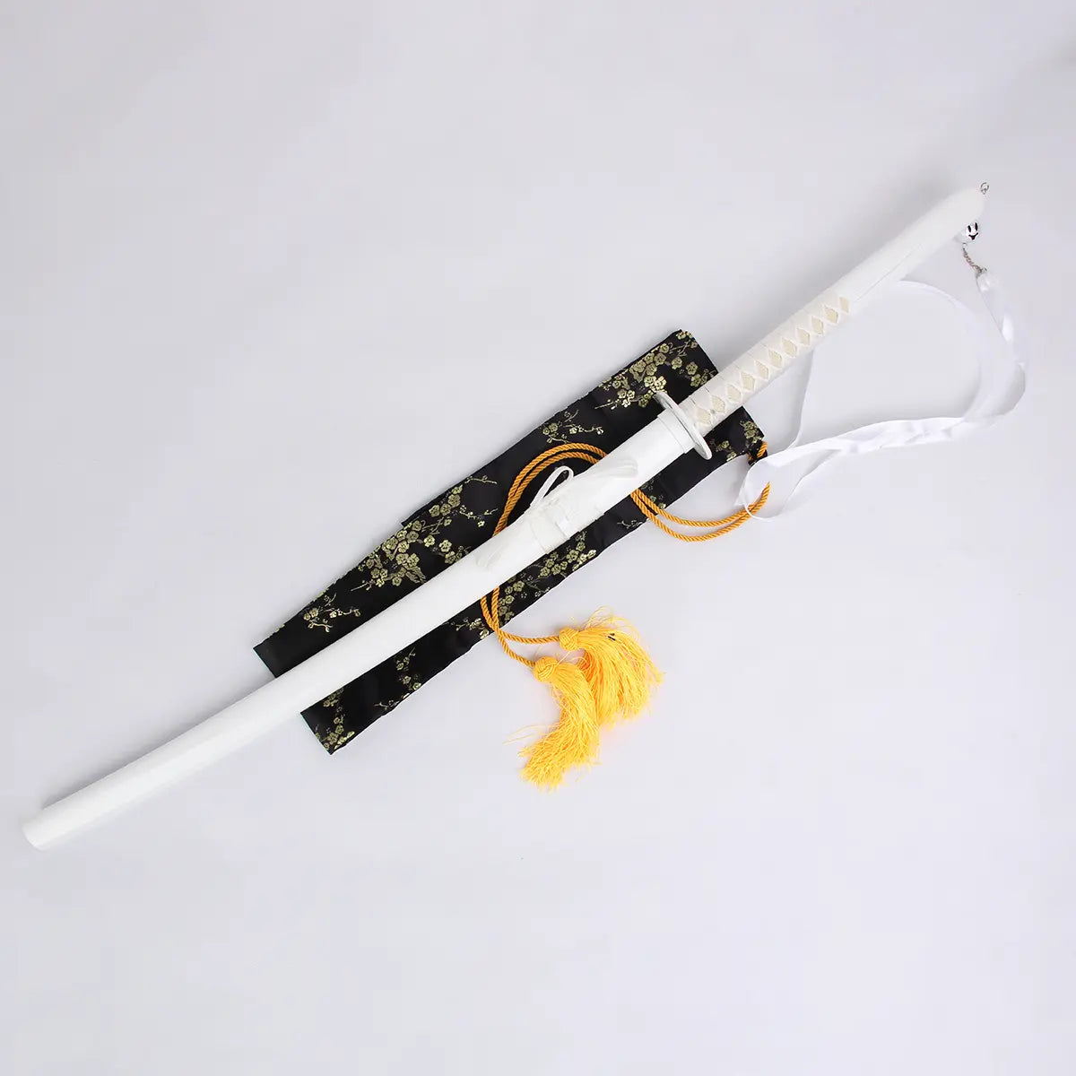 Photo du katana Kuchiki Rukia “Sode no Shirayuki” de Bleach, réplique zanpakutō Bankai inséré dans son fourreau blanc, poignée blanche, posé sur une sacoche noire brodée, décor sur fond clair.