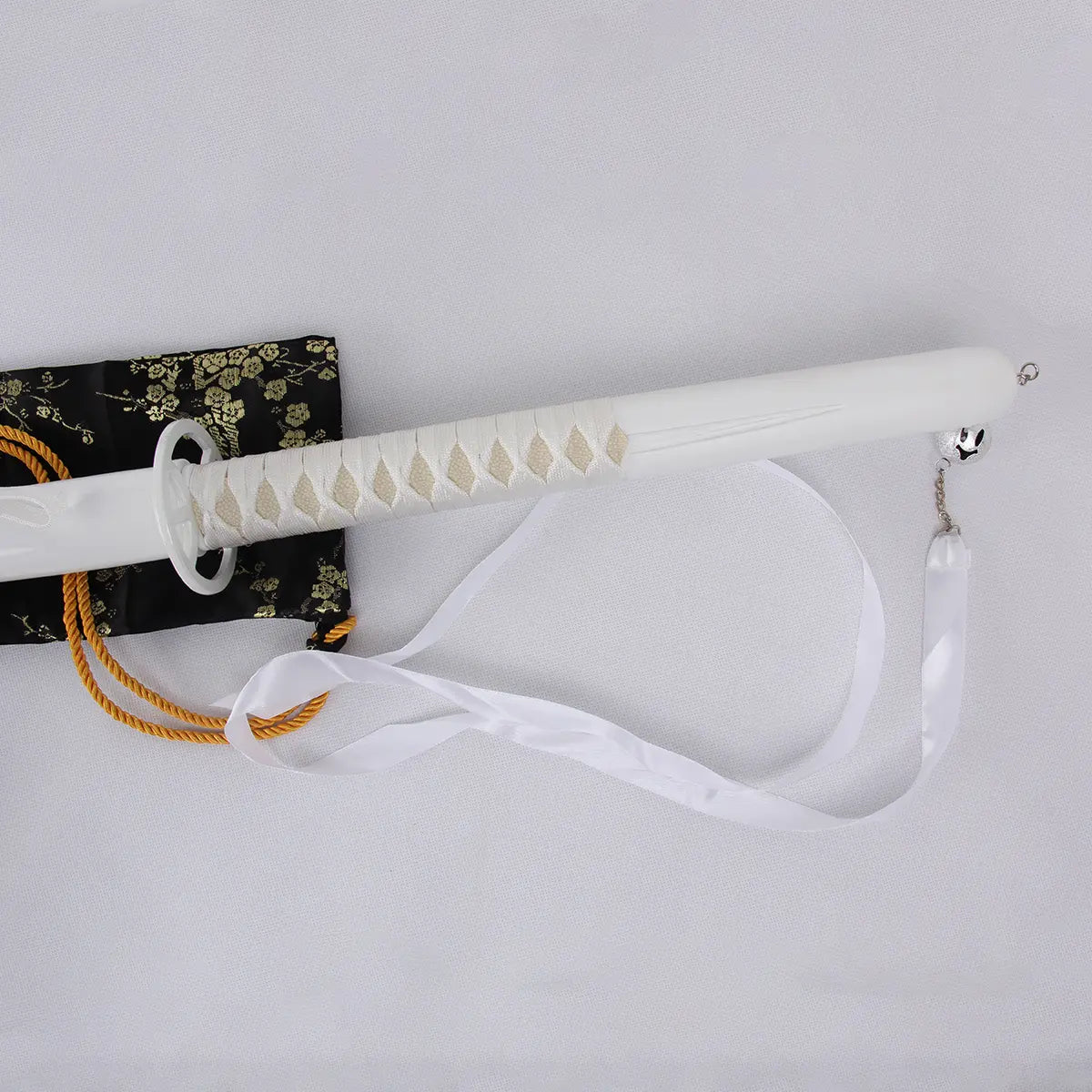 Vue du katana Kuchiki Rukia “Sode no Shirayuki” de Bleach, gros plan sur la poignée blanche tressée avec ruban blanc et pommeau métallique, posé sur une housse noire à motifs dorés, fond clair.