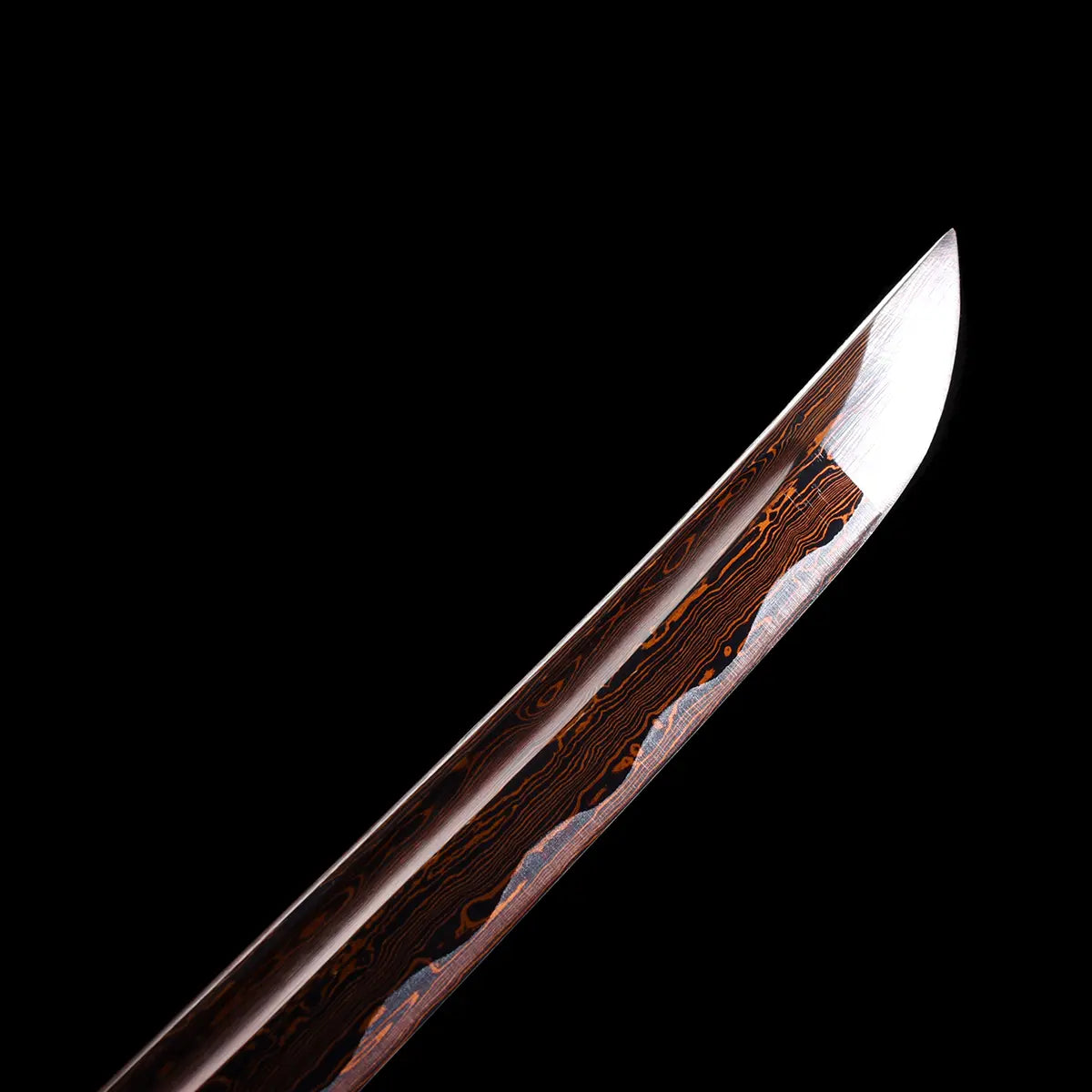 Gros plan sur la pointe du katana japonais Ryū Honō, lame damas rouge-feu polie avec hamon visible, sur fond noir. Photographie studio Blade Bushido mettant en valeur les reflets du tranchant et la texture veinée du métal forgé.