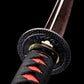 Gros plan sur la garde tsuba du katana japonais Ryū Honō, ornée d’un dragon sculpté en relief, lame damas rouge-feu et poignée tsuka noire tressée de rouge. Fond noir studio Blade Bushido soulignant les détails métalliques et la finition artisanale du sabre.