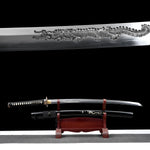 Composition double montrant le katana japonais artisanal Ryū no Ken sur fond noir, avec en partie supérieure un gros plan de la lame en acier poli présentant une longue gravure dragon en relief, et en partie inférieure le katana dégainé exposé sur un support en bois verni rouge, fourreau noir laqué décoré d’un motif dragon placé en dessous, manche noir tressé avec losanges blancs en peau de raie, habaki doré visible, surface inférieure gris clair, mise en scène mettant en valeur à la fois le détail de la gr