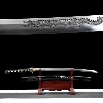 Composition double montrant le katana japonais artisanal Ryū no Ken sur fond noir, avec en partie supérieure un gros plan de la lame en acier poli présentant une longue gravure dragon en relief, et en partie inférieure le katana dégainé exposé sur un support en bois verni rouge, fourreau noir laqué décoré d’un motif dragon placé en dessous, manche noir tressé avec losanges blancs en peau de raie, habaki doré visible, surface inférieure gris clair, mise en scène mettant en valeur à la fois le détail de la gr
