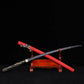 Japanese katana Sakura no Ken displayed crossed on a wooden stand, black background, unsheathed black blade with engraved floral sakura pattern, red leather wrapped saya positioned diagonally, black and white tsuka handle visible, traditional samurai sword presentation with strong contrast
