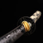 Close-up of Japanese katana Sakura no Ken guard and blade base, black background, black round tsuba with engraved pattern, golden habaki fitted at the blade base, black steel blade with floral sakura engraving visible, traditional samurai sword fittin
