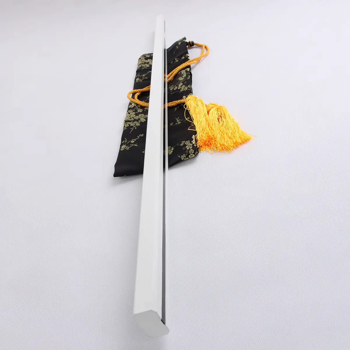 Vue de profil du katana Sasuke Uchiwa Kusanagi de Naruto, fourreau blanc rectiligne posé sur une housse en soie noire à motifs dorés avec cordon jaune, réplique en acier carbone 1045 haut de gamme idéale pour collection et cosplay.