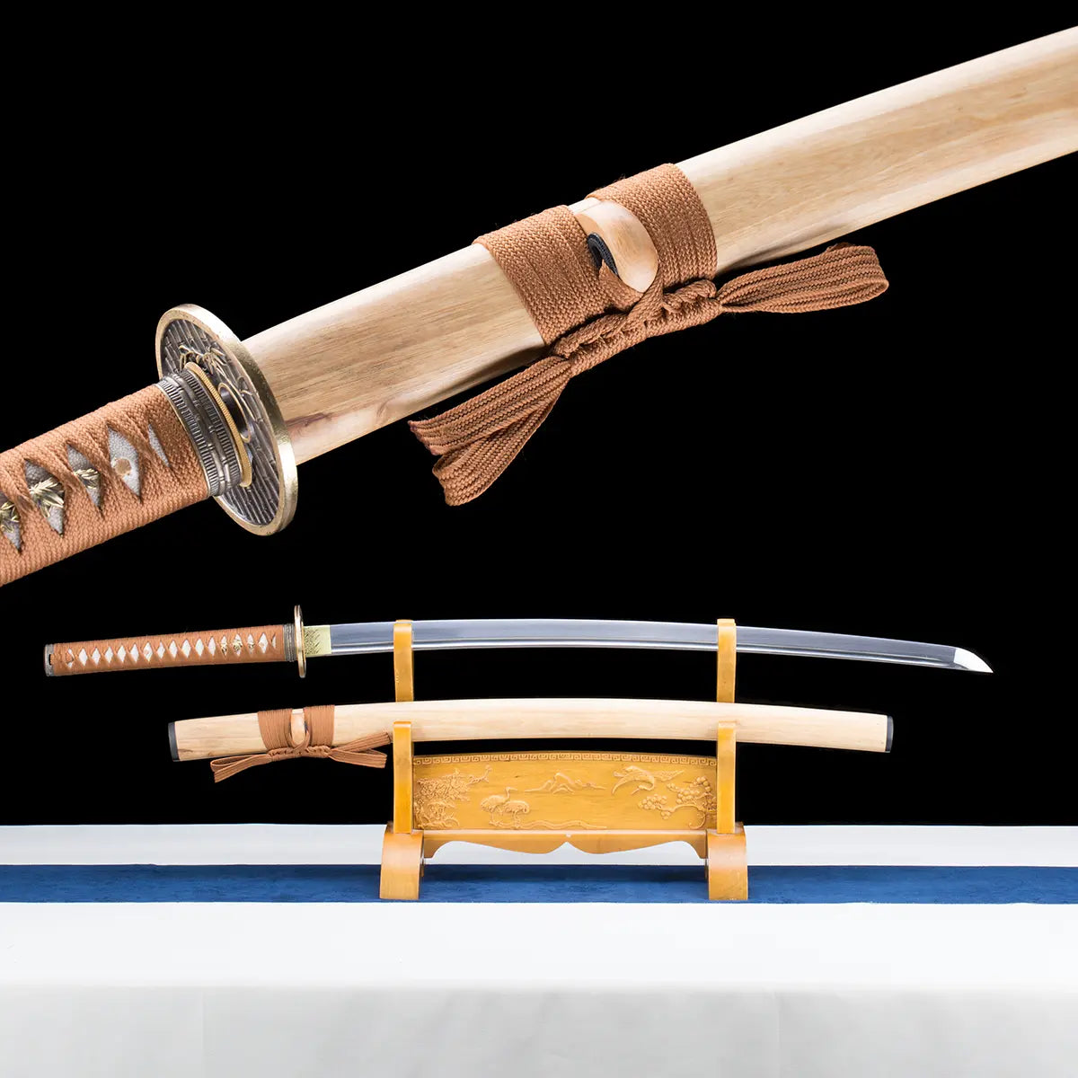 Composite view of the Japanese artisanal katana Take no Kaze photographed on a deep black background. The image combines a close-up of the bamboo scabbard with brown woven sageo tied around the kurigata and a full display view of the katana on a wooden stand. The polished steel blade with visible fuller is shown above the natural light bamboo saya, while the handle is wrapped in brown synthetic leather ito over white ray skin, featuring a round dark metal tsuba and brass-colored habaki, highlighting the tra