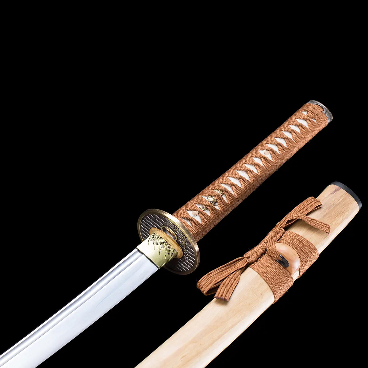 Detail view of the Japanese artisanal katana Take no Kaze photographed on a deep black background, showing the polished steel blade next to the natural light bamboo scabbard. The saya features a visible wood grain and a brown woven sageo tied around the kurigata. The handle is wrapped in brown synthetic leather ito over white ray skin, with decorative metal menuki, a round dark metal tsuba, and a brass-colored habaki, highlighting the tradit
