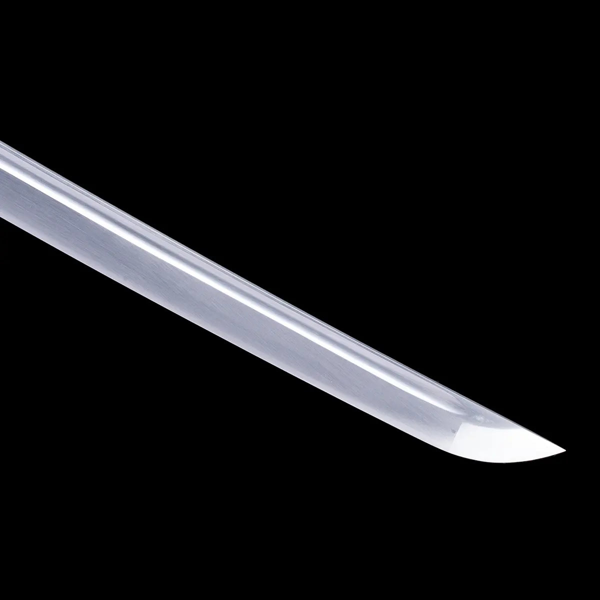 Close-up of the Japanese artisanal katana Take no Kaze blade tip photographed on a deep black background. The image shows the polished steel blade with a clean reflective surface and a visible fuller running along the length. The curved kissaki is clearly defined, with a sharp edge and smooth geometry, highlighting the functional finish and traditional katana profile without hamon.

