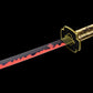 Gros plan de la garde dorée et de la lame noire et rouge du katana Yoriichi, sabre Demon Slayer décoratif collector.