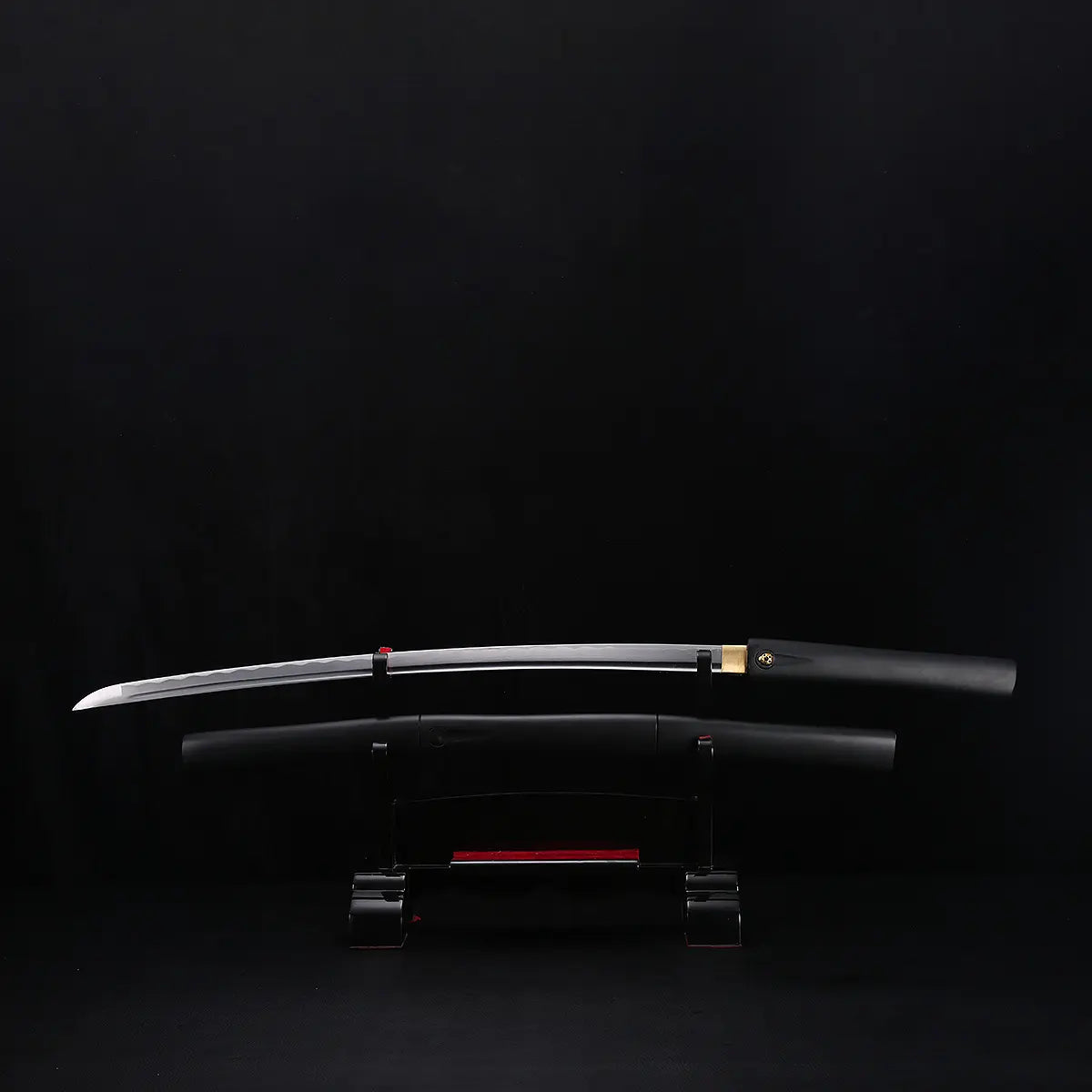 Katana shirasaya noir KUROTAKE avec la lame sortie du fourreau, présenté horizontalement sur un support sombre, fond noir uniforme, lame en acier poli visible avec courbure marquée, fourreau et poignée en bois dur laqué noir imitation bambou, habaki en laiton apparent, ensemble sans tsuba.
