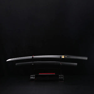 Katana shirasaya noir KUROTAKE avec la lame sortie du fourreau, présenté horizontalement sur un support sombre, fond noir uniforme, lame en acier poli visible avec courbure marquée, fourreau et poignée en bois dur laqué noir imitation bambou, habaki en laiton apparent, ensemble sans tsuba.
