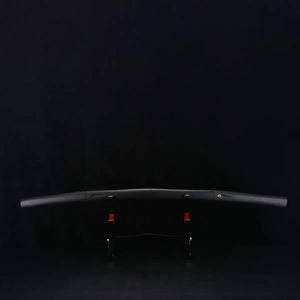 Katana shirasaya noir KUROTAKE posé sur un support en bois sombre, photographié sur fond noir, montrant le fourreau et la poignée en bois dur laqué noir imitation bambou, ligne courbe du saya visible, insert décoratif discret sur la poignée, présentation horizontale sans tsuba.
