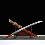 Sabre chinois Dao LONG FENG présenté en diagonale avec lame courbe sortie du fourreau, posé sur un support en bois devant un fond noir, avec fourreau rouge-brun, poignée assortie, garde noire et garnitures dorées décoratives visibles.