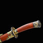 Gros plan sur la poignée rouge-brun du sabre chinois Dao LONG FENG, avec garde noire ornée de motifs dragon et phénix dorés, pommeau décoré, fourreau partiellement visible et fond noir sobre.