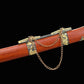 Gros plan sur le fourreau rouge-brun du sabre chinois Dao LONG FENG, avec texture bois visible, garnitures noires et dorées sculptées, chaînes décoratives métalliques et fond noir sobre.