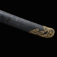 Gros plan sur l’extrémité du fourreau noir texturé du sabre chinois Dao LONG WEI, avec embout en laiton doré décoré de motifs dragon, finition sombre à points clairs et détail du fourreau sur fond noir.
