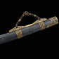 Gros plan sur le fourreau noir texturé du sabre chinois Dao LONG WEI, avec garnitures en laiton doré ornées de dragons, poignée de transport tressée brune, embout décoré et motifs métalliques visibles sur fond noir.
