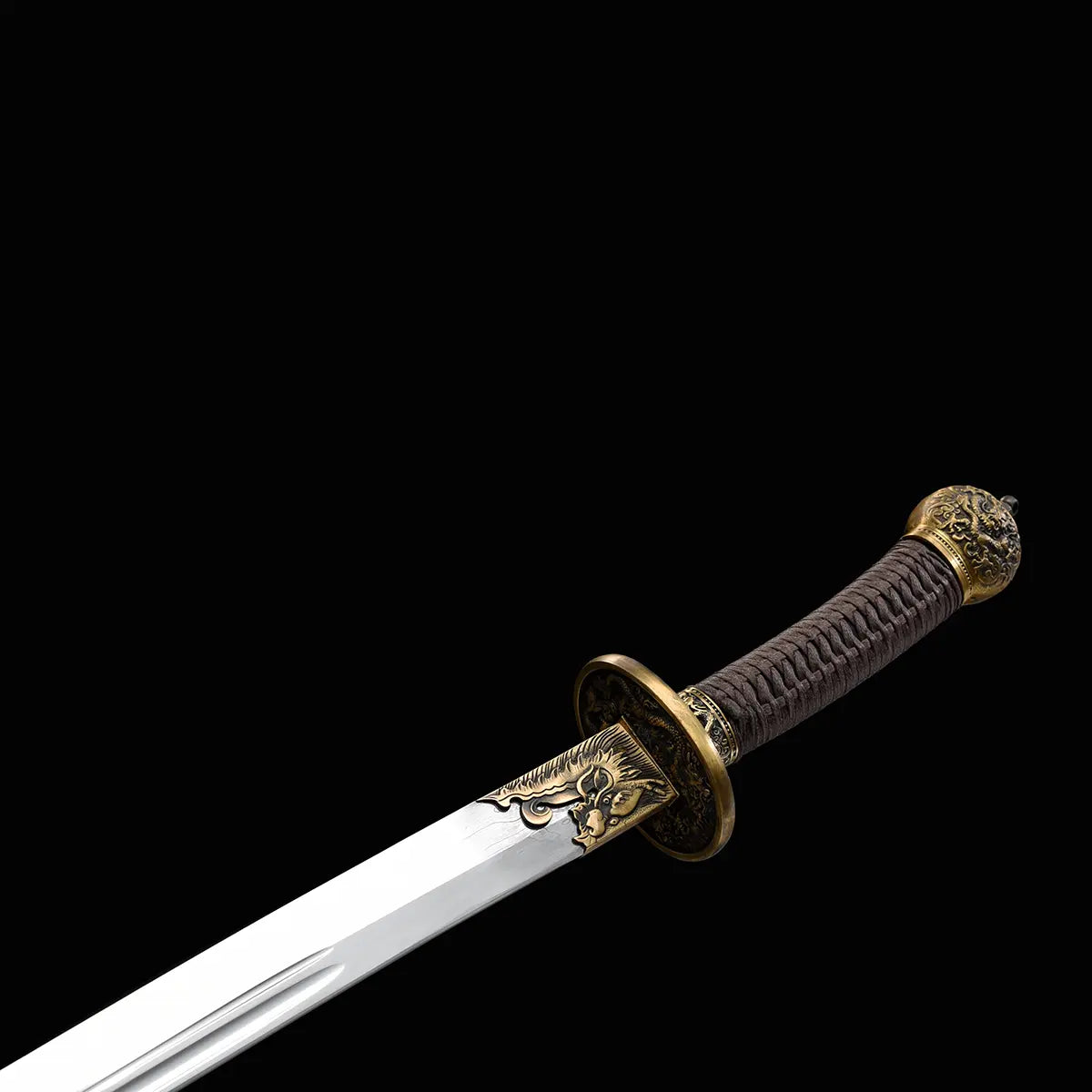 Gros plan sur le sabre chinois Dao LONG WEI avec poignée brune tressée, pommeau décoré, garde ronde en laiton, ornements dorés à la base de la lame et lame courbe argentée avec gorge centrale sur fond noir.