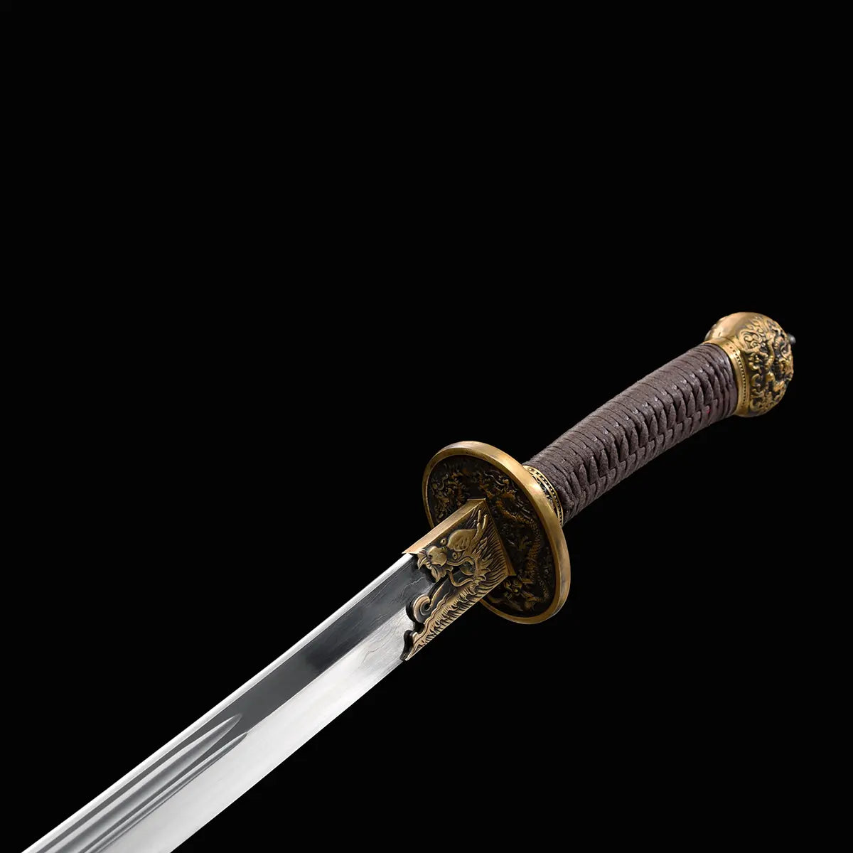 Gros plan sur le sabre chinois Dao LONG WEI avec poignée brune tressée, pommeau décoré, garde ronde en laiton ornée de dragons, base de lame gravée et lame courbe argentée avec gorge centrale sur fond noir.