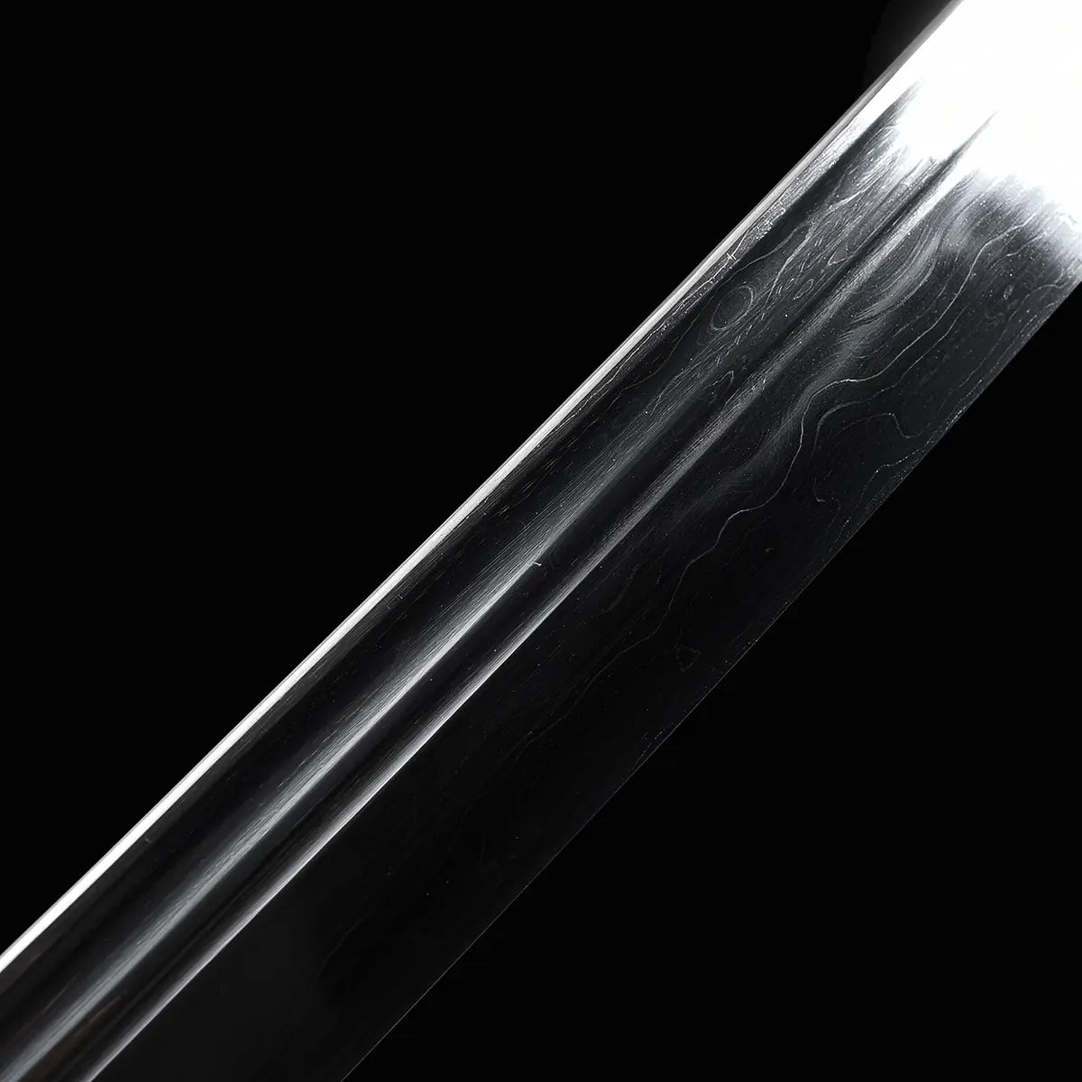 Gros plan sur la lame du sabre chinois Dao LONG WEI, avec gorge centrale, reflets sombres sur fond noir et motifs ondulés visibles de l’acier plié sur la surface de la lame courbe.