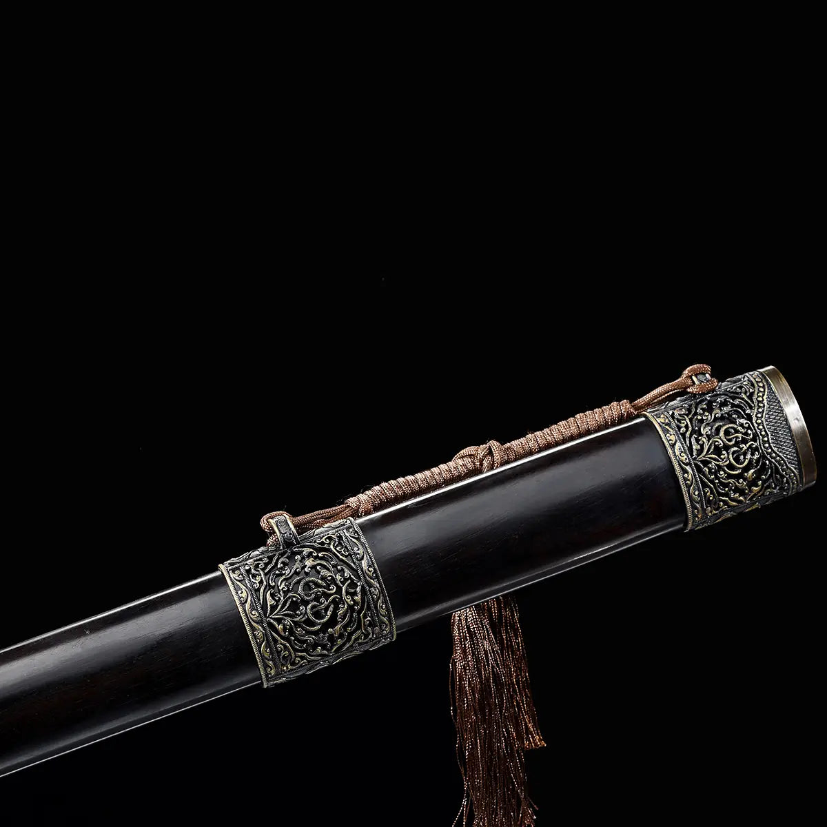 Détail du fourreau d’une épée chinoise Jian Longquan, avec bois sombre type ébène, garnitures métalliques ornementées, cordon brun, pompon traditionnel et fond noir.