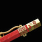 Gros plan sur le fourreau rouge texturé de l’épée chinoise Jian LONGQUAN HONG LONG, avec garniture dorée, motif géométrique, corde décorative jaune et finition brillante sur fond noir.