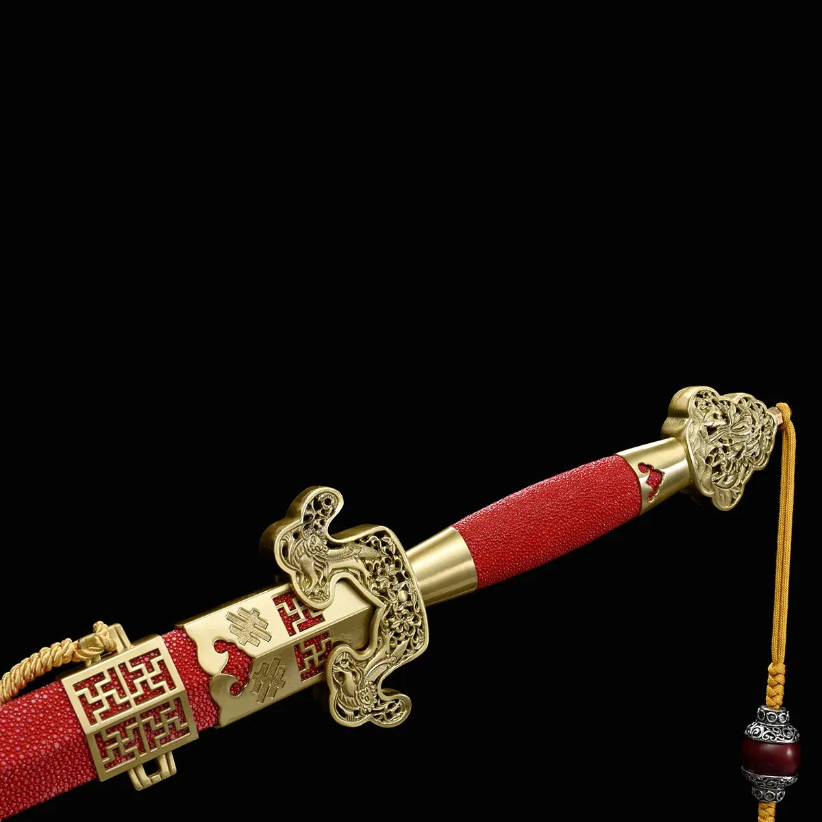 Gros plan sur l’épée chinoise Jian LONGQUAN HONG LONG dans son fourreau rouge texturé, avec garde dorée ouvragée, poignée rouge, garnitures en laiton et dragonne jaune avec perle décorative sur fond noir.